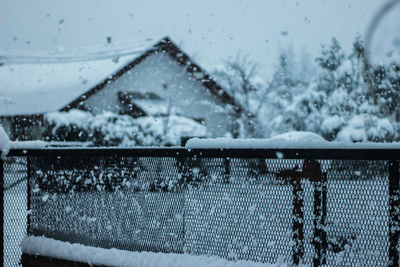 Close-up of snow on house against sky during winter