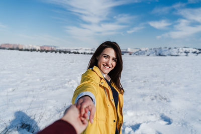 Portrait of smiling woman holding man hand in snow