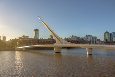 Bridge over river in city against clear sky