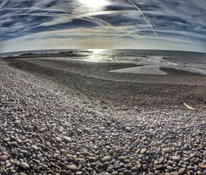 Scenic view of beach against cloudy sky