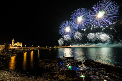 Firework display over river against sky at night