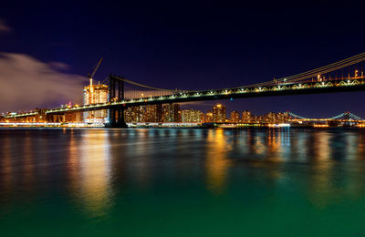 Illuminated manhattan bridge over river at night