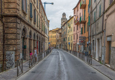 Empty road amidst buildings in city