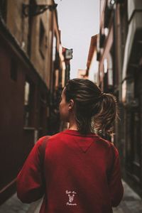 Rear view of woman standing on street against buildings in city