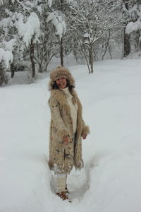 Portrait of cheerful woman standing on snow covered field