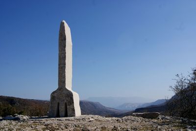 Built structure on countryside landscape against clear blue sky