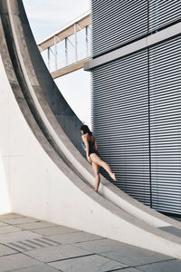 Woman dancing against wall in city