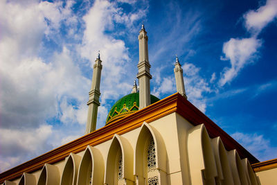 Low angle view of mosque against cloudy sky