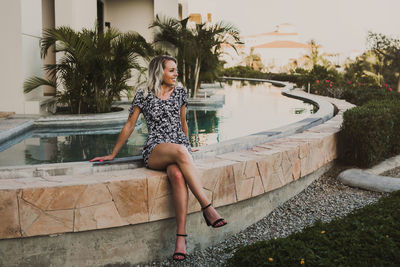 Woman sitting by tree against plants