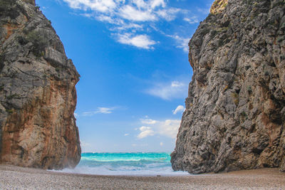 Rock formation on beach against sky