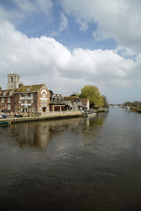 Buildings by river against sky