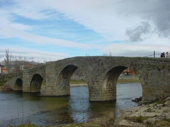 Arch bridge over river against sky