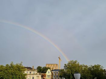 Low angle view of rainbow over buildings against sky