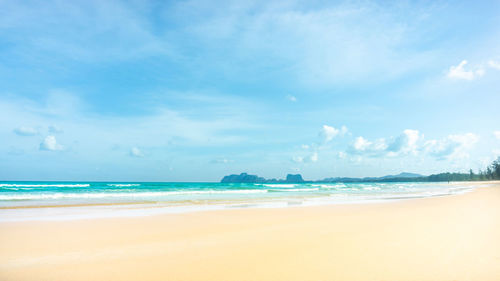 Scenic view of brown sand beach  on blue sea against sky