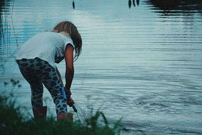 Rear view of girl standing by lake