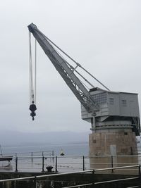 Low angle view of crane at construction site against sky