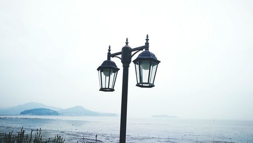 Street light by sea against clear sky