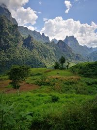 Scenic view of green landscape and mountains against sky