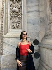 Portrait of young woman standing against wall