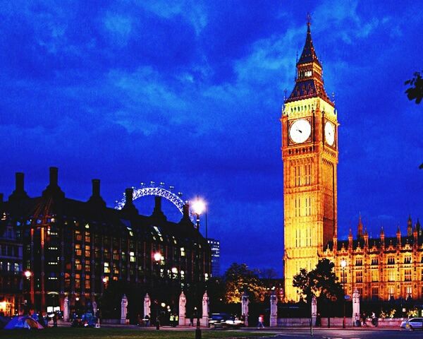 building exterior, architecture, built structure, illuminated, sky, city, night, blue, low angle view, clock tower, travel destinations, famous place, dusk, tower, city life, cloud - sky, tourism, outdoors, large group of people