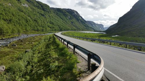 Scenic view of road by mountain against sky