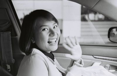 Side view of cheerful woman waving in car