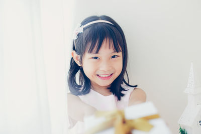 Portrait of cute girl standing against wall