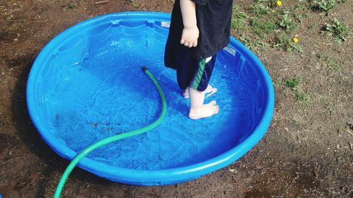 Low section of boy standing in wading pool