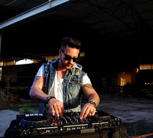 Male dj playing music on turntable in abandoned building