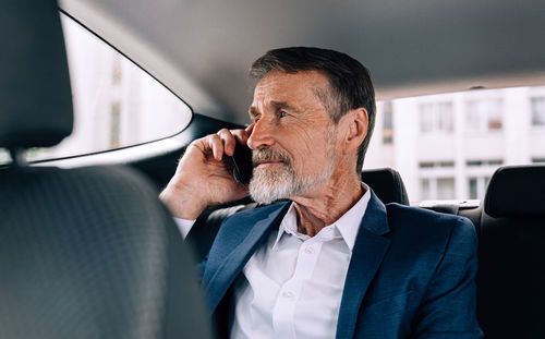 Businessman talking over mobile phone in car