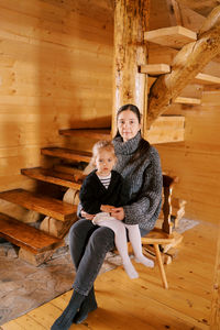 Full length of young woman sitting on hardwood floor