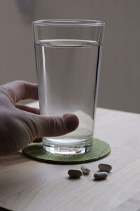 Cropped hand having pills and water at home
