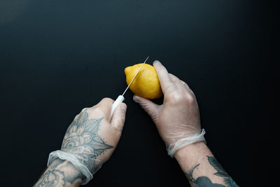 Close-up of hand holding fruit against black background