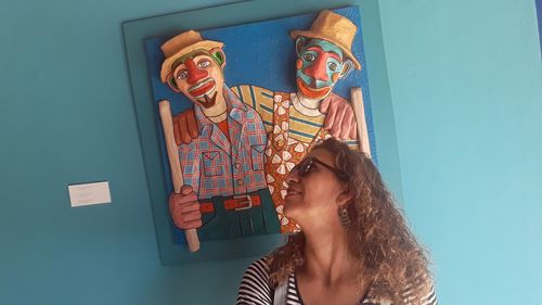 Portrait of smiling young woman standing against wall