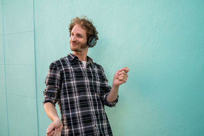 Smiling young man standing against wall