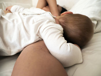 Woman with baby girl sleeping on bed