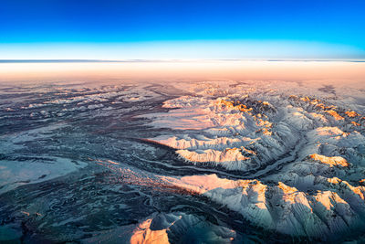 Aerial view of snowcapped landscape against sky during sunset