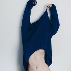 Woman holding blue t-shirt standing against white background