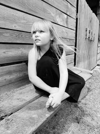 Young woman looking away while sitting on wood