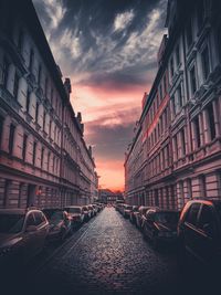 Street amidst buildings against sky during sunset