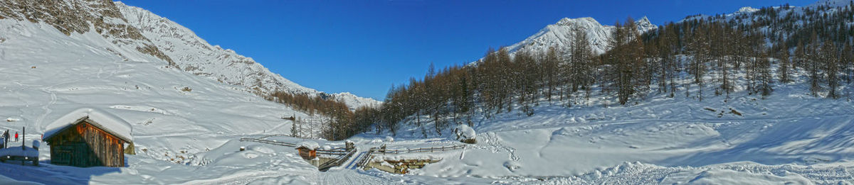 Snow covered landscape against clear blue sky