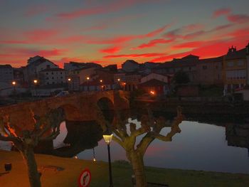 Illuminated city against sky at sunset