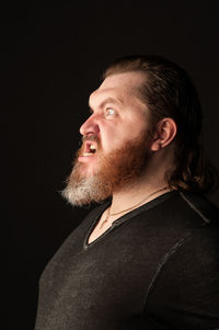 Portrait of man looking away against black background