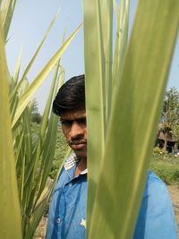 Portrait of young man standing against plants