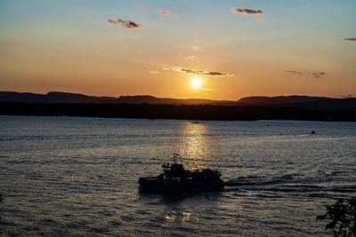 Silhouette people sailing on sea against sky during sunset