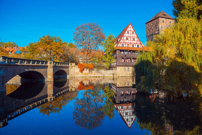 Arch bridge over canal by building against blue sky