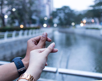 Midsection of person hand on railing against blurred water