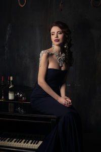 Beautiful woman in gown sitting on table at home