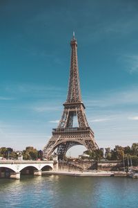 Arch bridge over river against sky in city