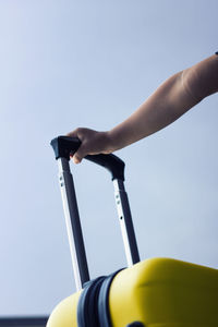 Close-up of child holding a handle of a suitcase.